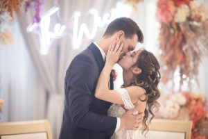 Bacio degli sposi sotto l'insegna neon al ricevimento