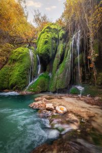 Cascata tra le rocce coperte di muschio in autunno
