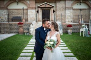 Bacio degli sposi nel giardino della villa, tra vialetto in pietra e rose rosse