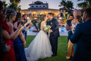 Bacio degli sposi fotografato dagli invitati con gli smartphone, piscina della villa sullo sfondo