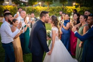 Bacio degli sposi tra gli invitati che scattano foto al tramonto