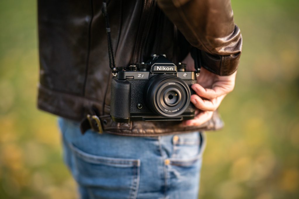 Nikon Zf carried at the hip on its strap, with a pancake lens mounted