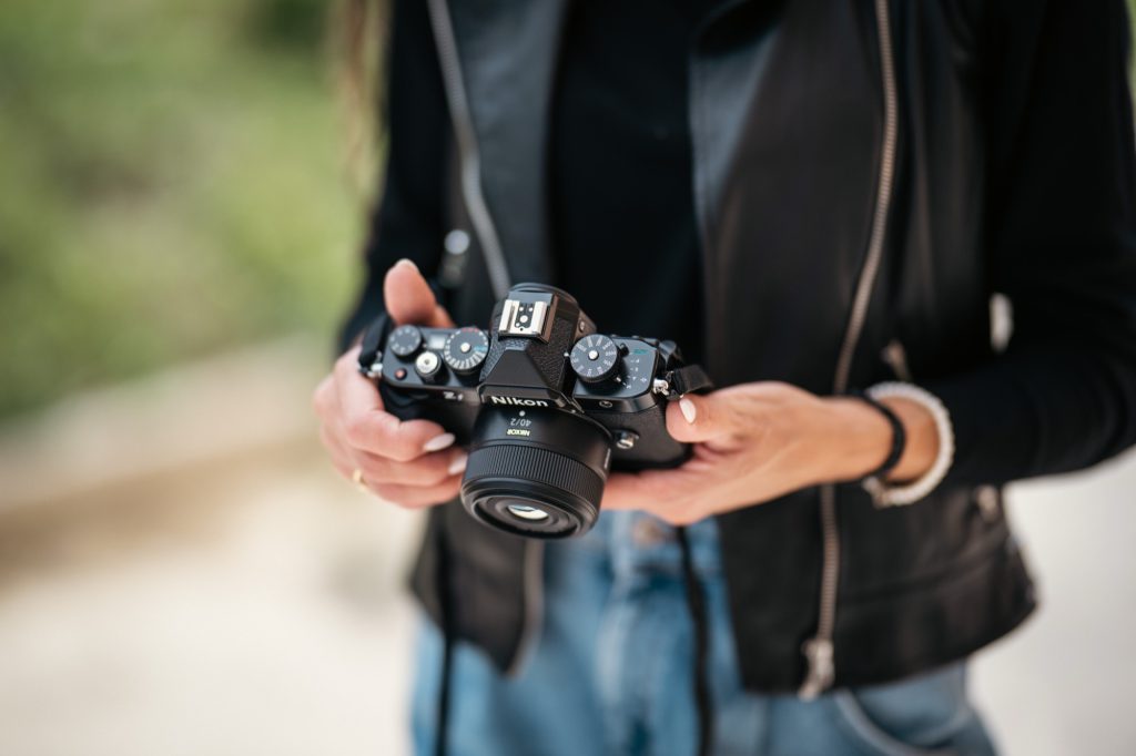 Nikon Zf with a compact lens held in both hands, showing the modest size of a full frame